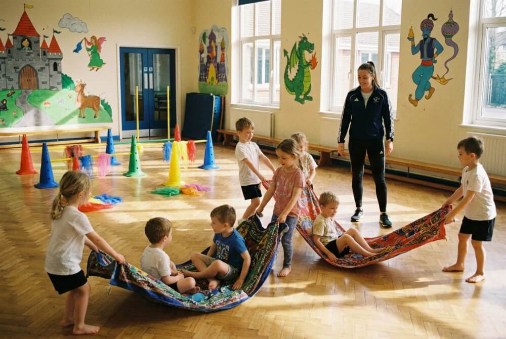 Dzieci bawiące się w lot na latających dywanach z kocyków w bajkowo udekorowanej sali