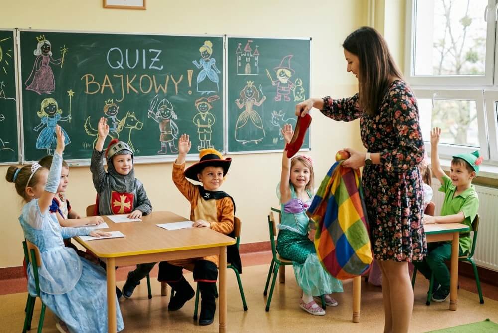 Nauczycielka pokazuje dzieciom pantofelek i jabłko z czarodziejskiego worka podczas quizu bajkowego
