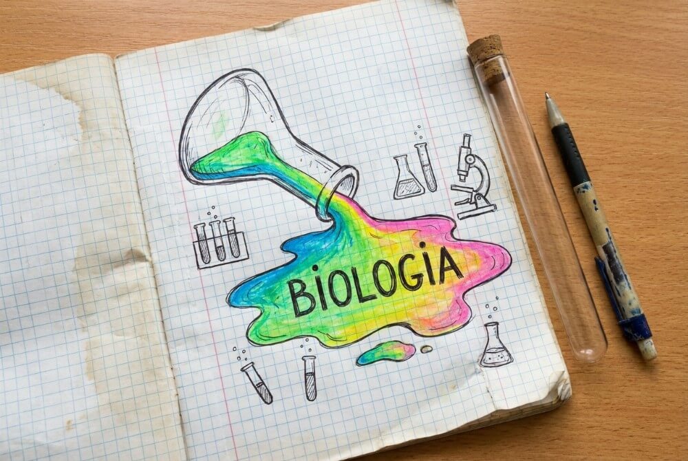 Tytułowa strona zeszytu z rozlaną kolorową „cieczą” z kolby, na której widnieje napis „Biologia”, oraz szkicami mikroskopu i probówek