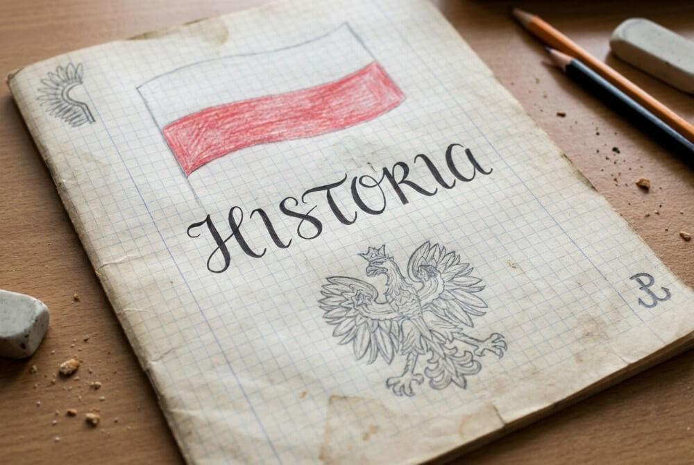Tytułowa strona zeszytu z napisem „HISTORIA”, flagą biało-czerwoną i szkicem Orła Białego.