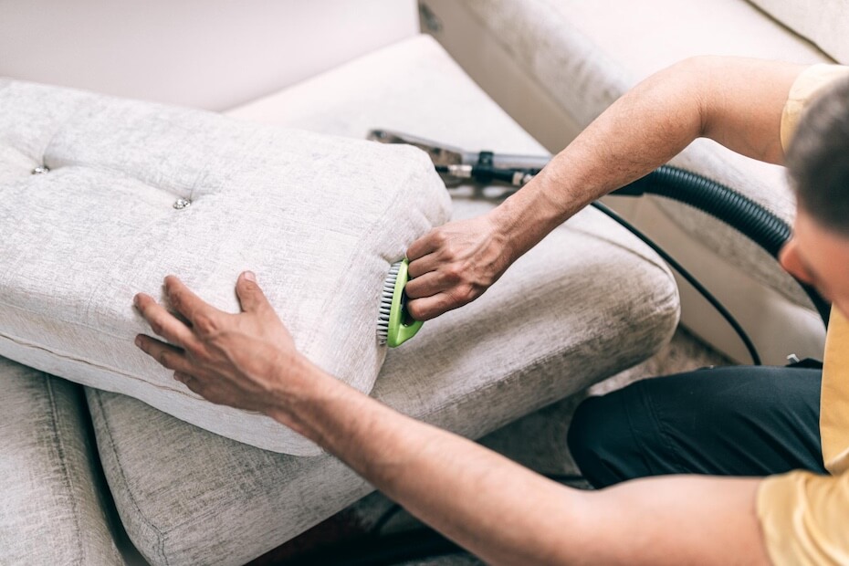 Mężczyzna szorujący szczotką kanapę